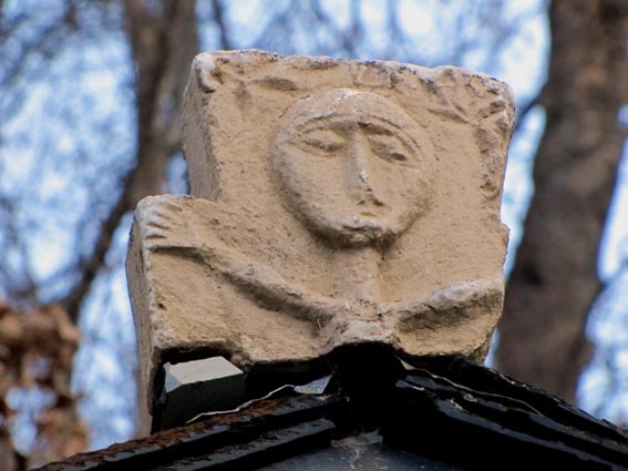 La pierre gravée, représentant un personnage naïf, placée au sommet de la toiture de la chapelle de Bayet.